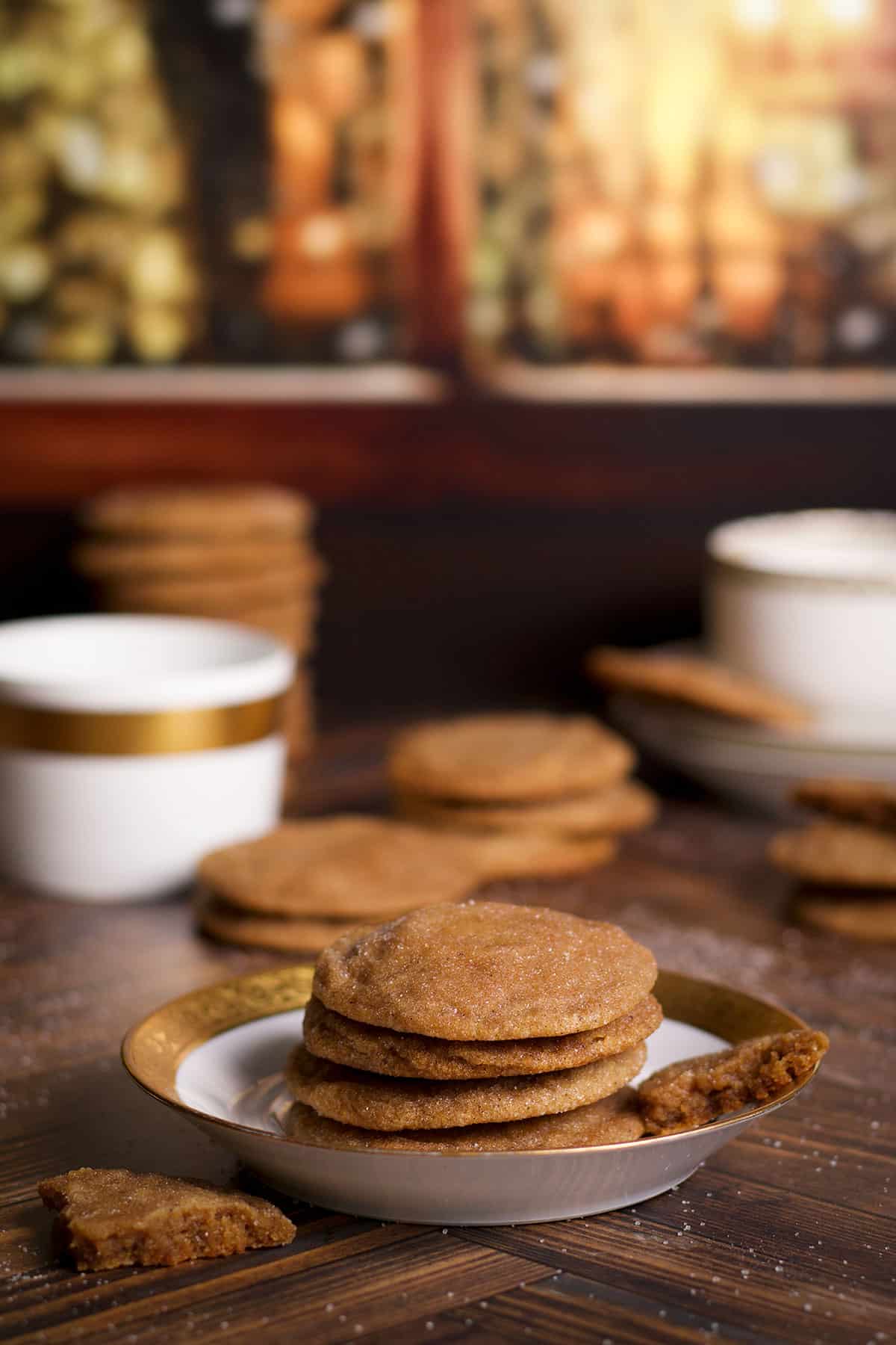 Several brown sugar cookies on a plate with stacks of cookies on the table around the plate.