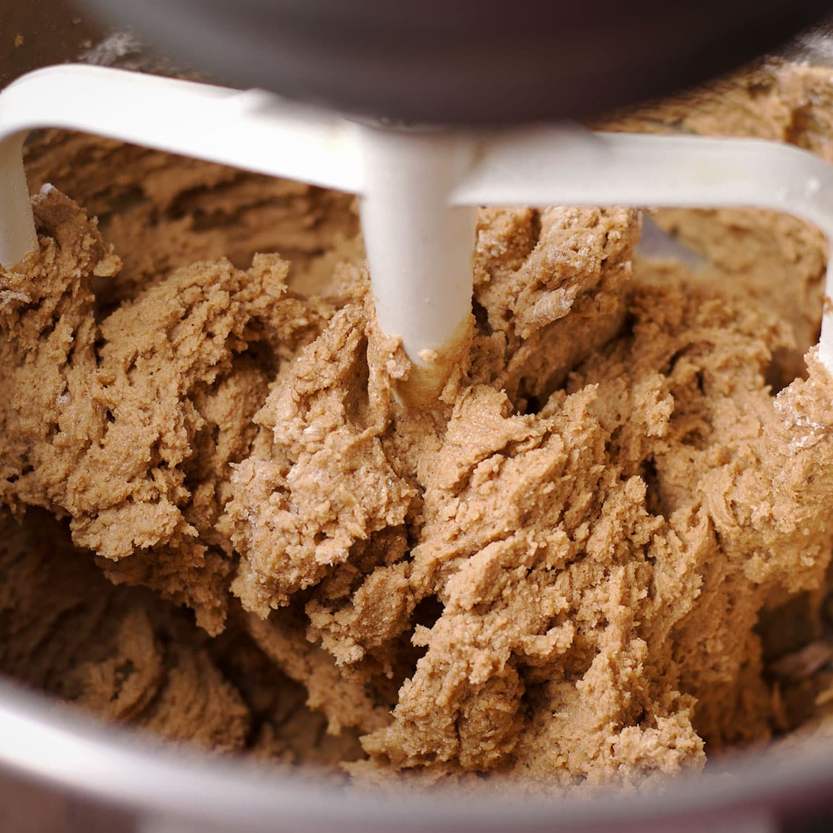 Using an electric mixer to gently mix the dry ingredients into brown sugar cookie dough.