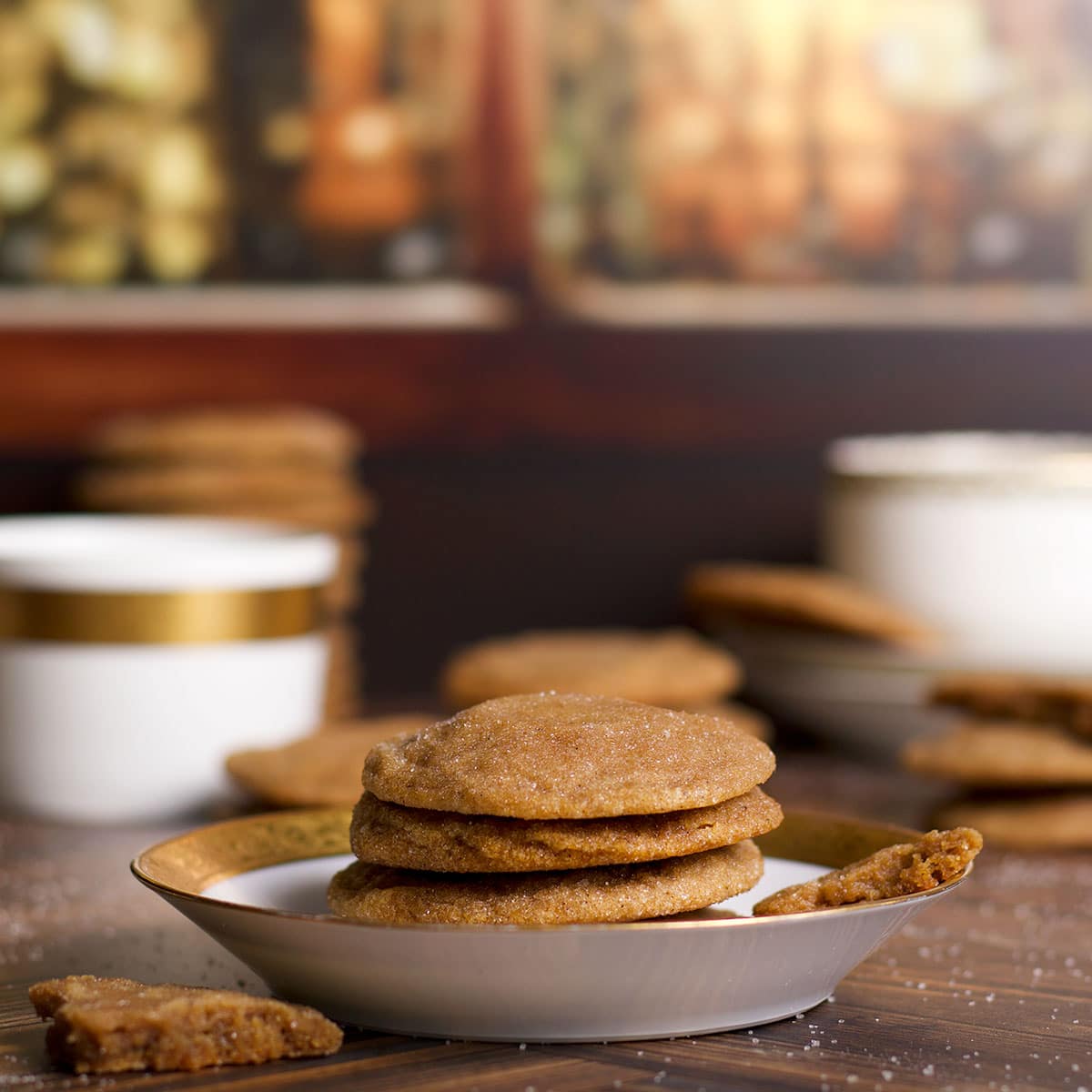 Several brown sugar cookies on a plate with stacks of cookies on the table around the plate.