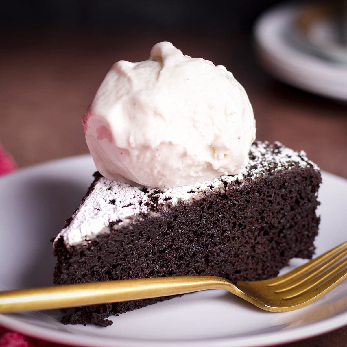 A slice of Dutch oven chocolate cake topped with a scoop of vanilla ice cream.
