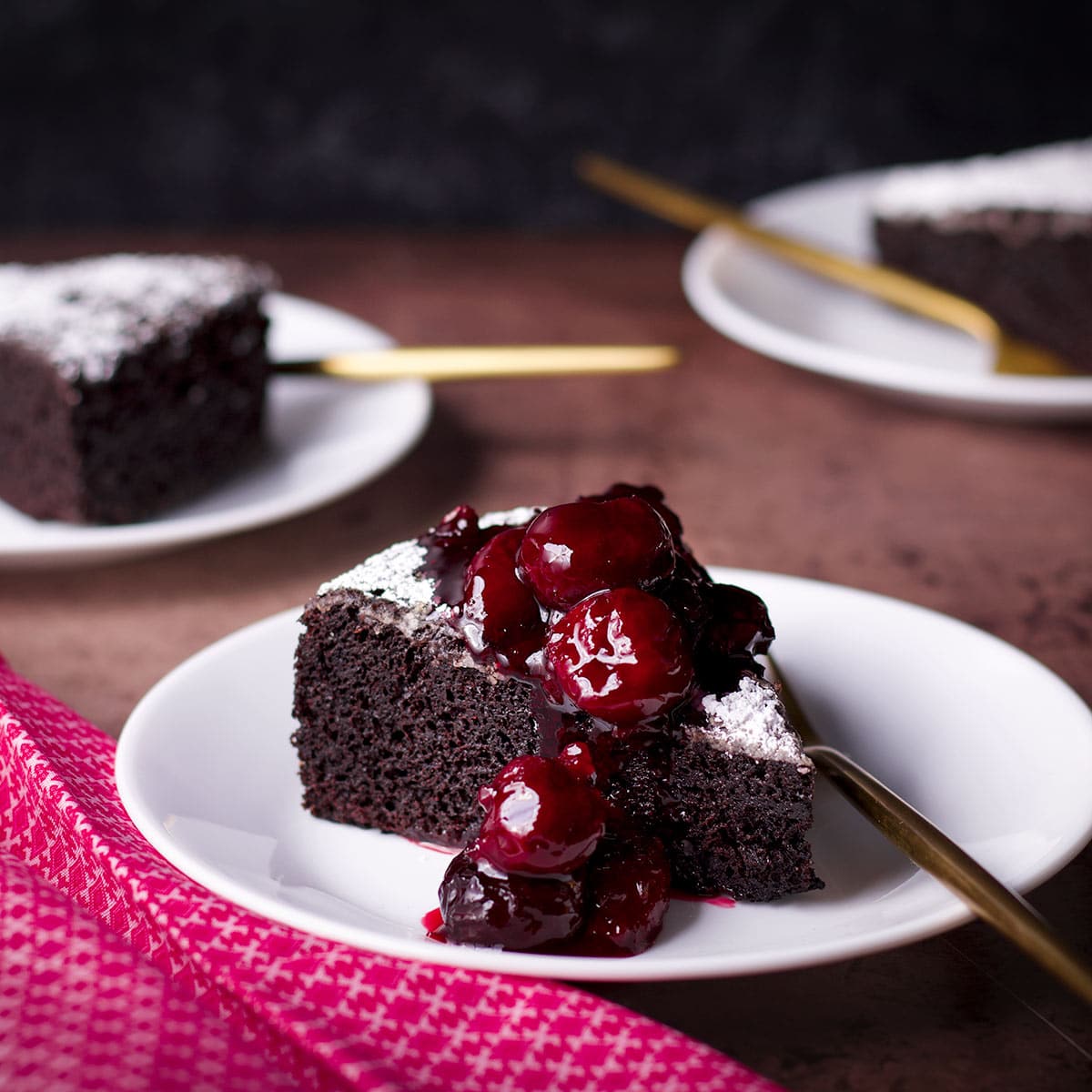 A slice of Dutch oven chocolate cake smothered in cherry sauce.
