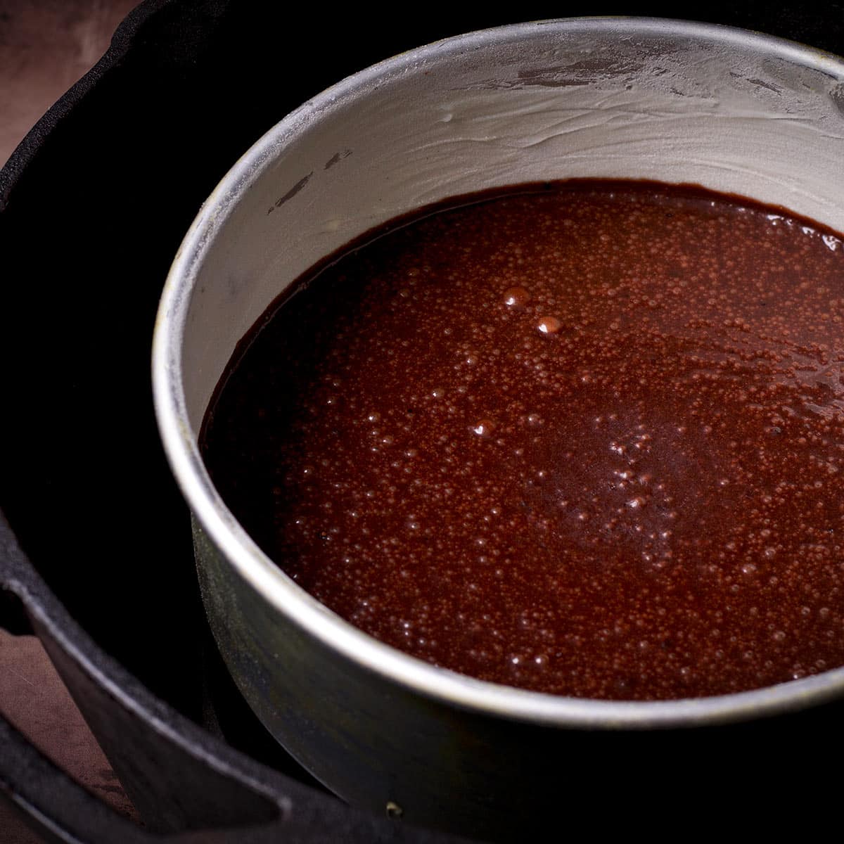 A pan of chocolate cake batter in the center of a Dutch oven.