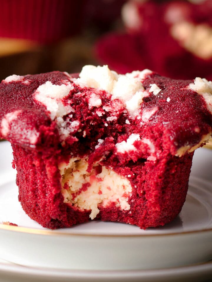 A red velvet muffin that's been broken in half to reveal the cream cheese filling in the center of the muffin.