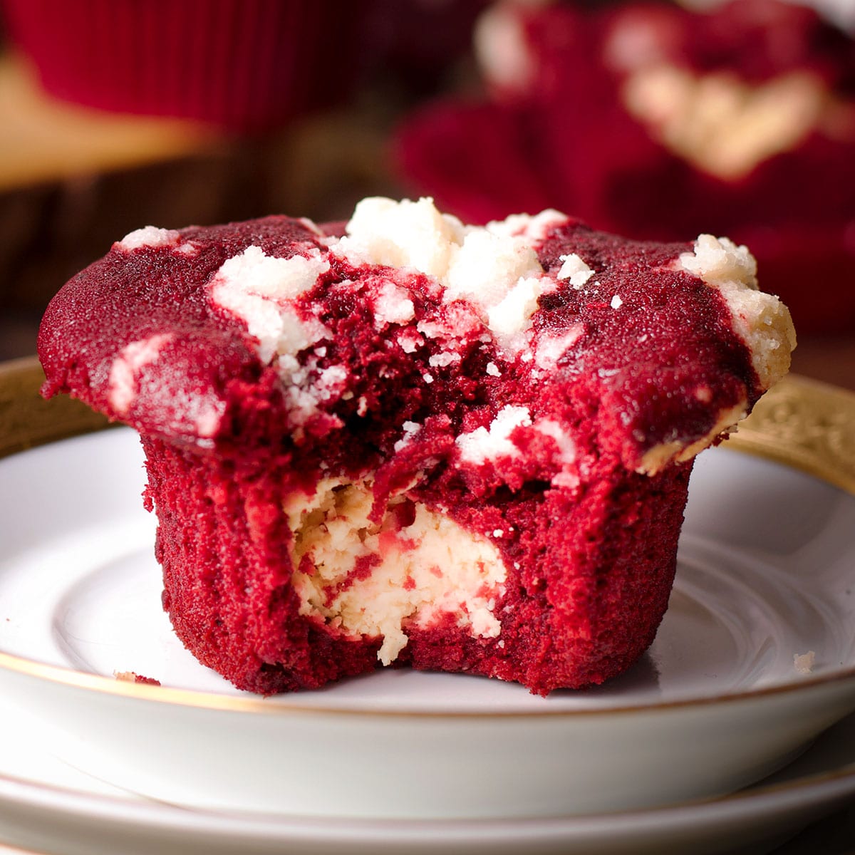 A red velvet muffin that's been broken in half to reveal the cream cheese filling in the center of the muffin.