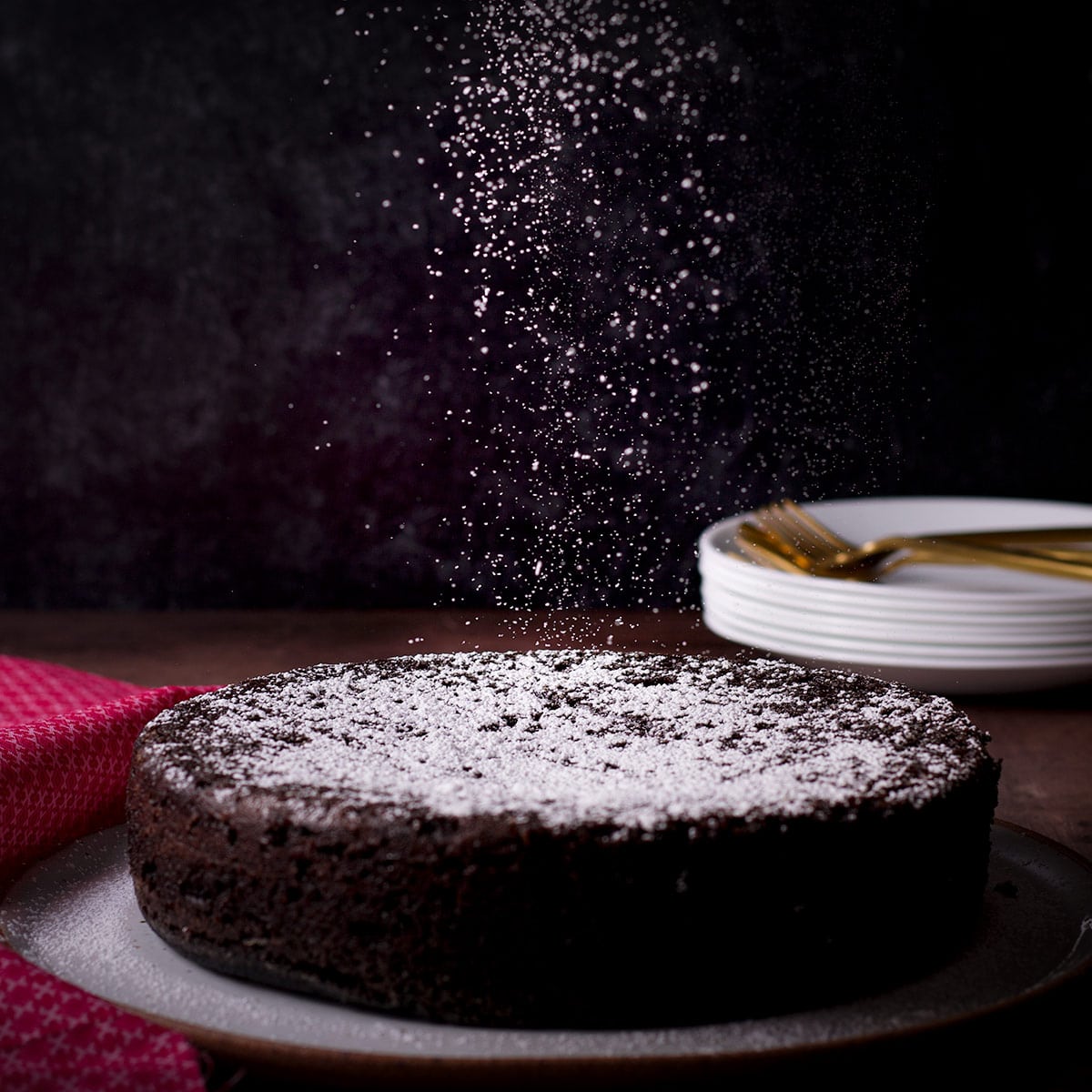 Sprinkling powdered sugar over the top of a Dutch oven chocolate cake.