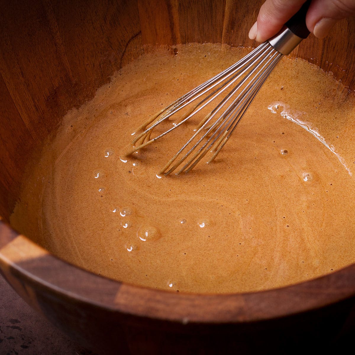Using a whisk to blend brown sugar and eggs.