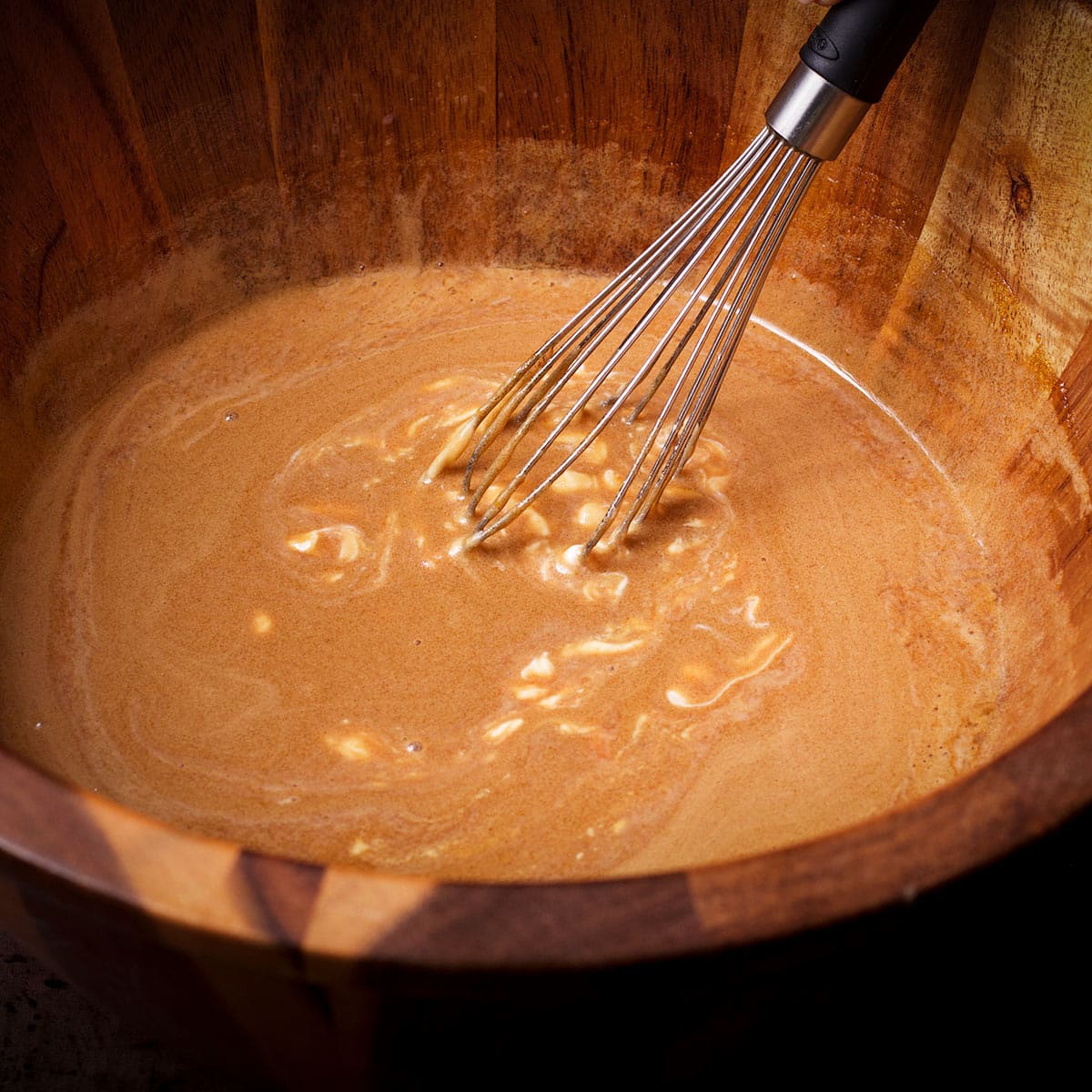 Using a whisk to mix sour cream into the batter for Dutch oven chocolate cake.