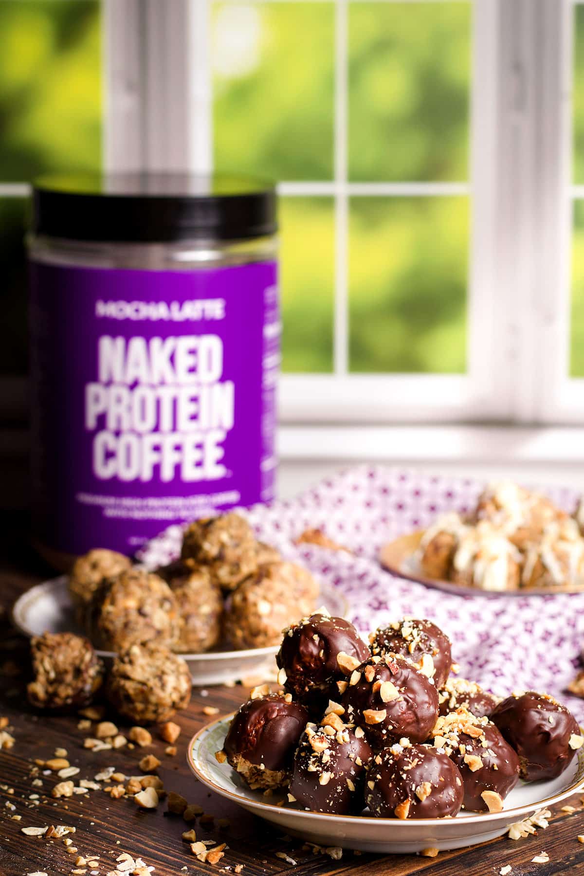 A plate of chocolate covered protein balls sprinkled with chopped peanuts.